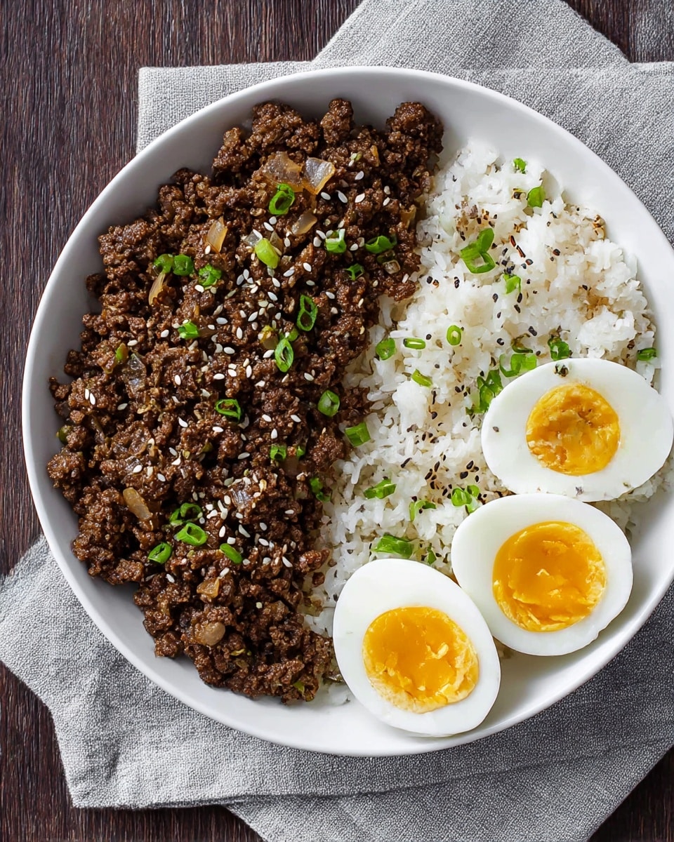 A white bowl contains three main layers arranged side by side: on the left is a heap of cooked ground beef mixed with small pieces of translucent onions and sprinkled with white sesame seeds and finely chopped green onions; in the middle is a portion of fluffy white rice with small bits of green onions on top; on the right are two halves of a soft-boiled egg with firm white outer layer and bright yellow, slightly runny yolk inside. The bowl rests on a grey cloth napkin placed on a dark wooden surface. Photo taken with an iphone --ar 4:5 --v 7