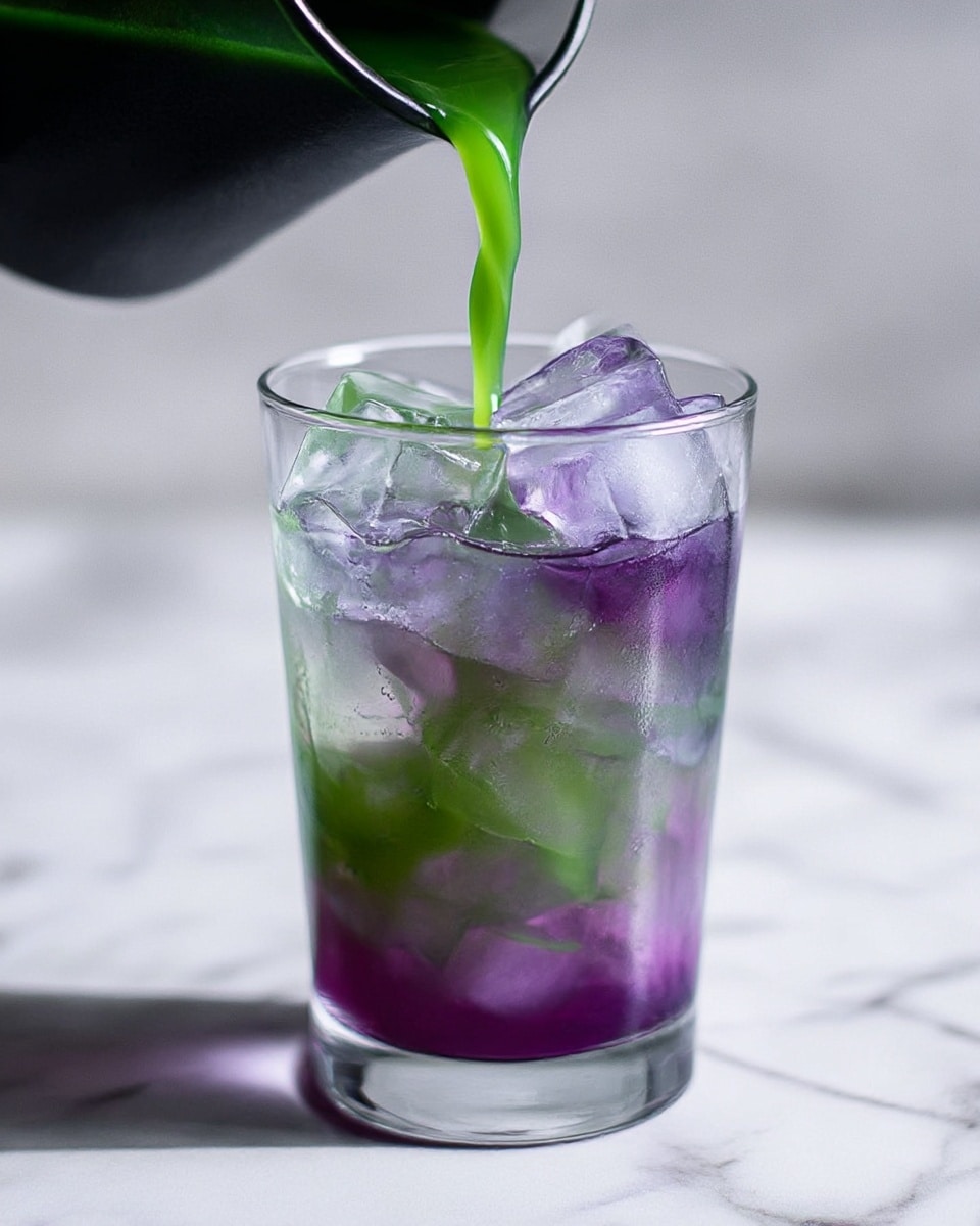 A clear glass filled with two layers of iced drink sits on a white marbled surface. The bottom layer is purple with ice cubes inside, and the top layer is green, being poured from a black container above. Large clear ice cubes float in the glass, mixing the bright green liquid with the purple base, creating a fresh and colorful look. Photo taken with an iphone --ar 4:5 --v 7
