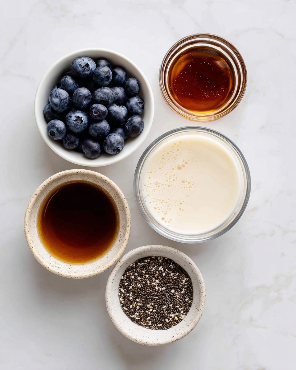 The image shows five small white bowls with different ingredients arranged on a white marbled surface. The bowl on the top left is filled with deep blue, round blueberries, looking fresh and plump. To its right, a bowl holds dark amber-colored maple syrup with a smooth, shiny surface. In the center, a clear glass bowl contains creamy, off-white almond milk with a few bubbles on top. Below that, on the left, there is a bowl filled with rich brown vanilla extract, visible through the textured sides. Finally, on the bottom right, a bowl holds small, mixed-color chia seeds, mostly dark with some lighter specks, showing a grainy texture. The bowls are staged neatly in a loose circle. Photo taken with an iphone --ar 4:5 --v 7