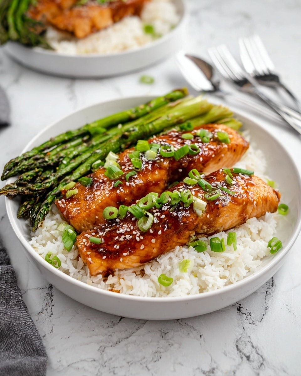 The image shows a white plate with three layers of food. The bottom layer is white rice, fluffy and spread evenly in the plate. On the left side, there is a layer of green grilled asparagus, placed in neat bunches. On top, there are two shiny, golden brown glazed salmon pieces, garnished with white sesame seeds and chopped green onions scattered over the salmon and rice. The plate is set on a white marbled surface with a blurred second plate and silver fork in the background. Photo taken with an iphone --ar 4:5 --v 7
