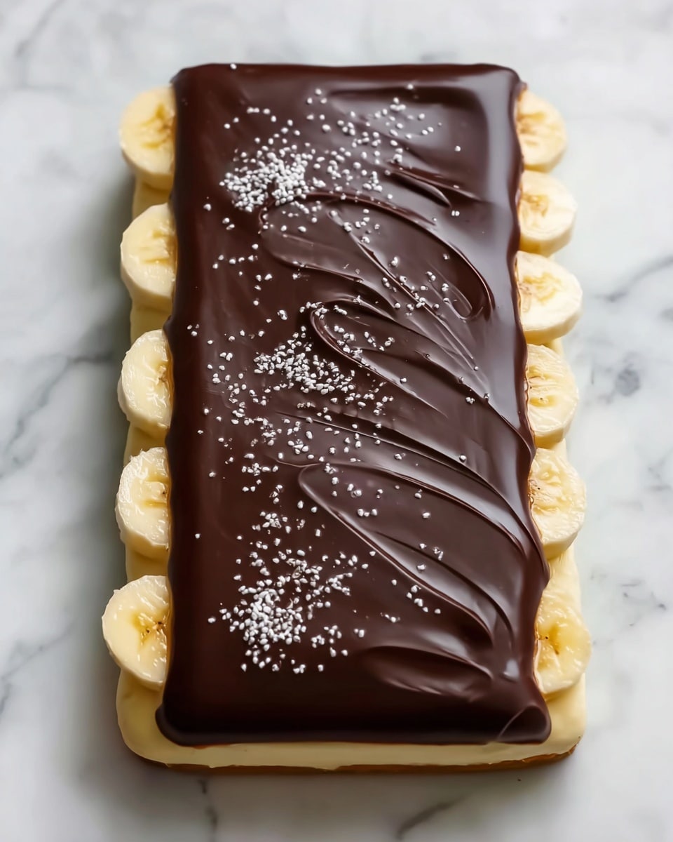 The image shows a rectangular dessert with three distinct layers on a white marbled surface. The bottom layer is slices of fresh banana, neatly arranged in a single row along the edges with a creamy light-yellow spread above it. The top layer is a thick, smooth dark chocolate covering with gentle swirls and small white sprinkles spread evenly over the surface, creating a rich and glossy finish. photo taken with an iphone --ar 4:5 --v 7