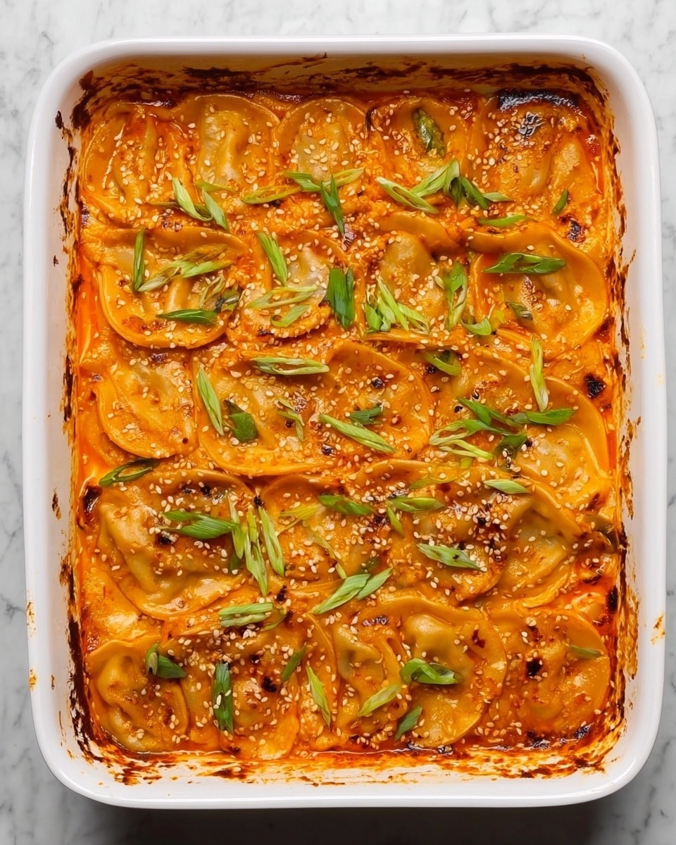 The image shows a white rectangular baking dish filled with a layered dish of dumplings in a bright orange sauce. The dumplings are arranged in overlapping rows, each piece golden brown with slightly crispy edges. The sauce is smooth, covering most of the dumplings partially, with small pieces of green onions and sesame seeds sprinkled evenly across the top. The dish looks warm and baked, with a few browned spots around the edges of the baking dish. The background shows a white marbled texture. photo taken with an iphone --ar 4:5 --v 7