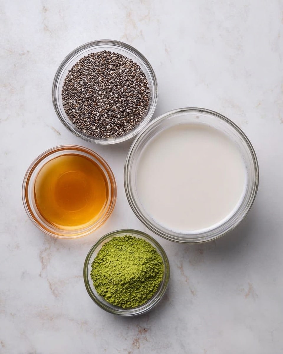 The image shows four clear glass bowls placed on a white marbled surface. The largest bowl, positioned on the right, is filled with a smooth, white liquid. Above and to the left of it is a medium bowl filled with small, dark chia seeds mixed with some lighter ones, creating a grainy texture. Below and slightly to the left of the chia seeds bowl is a small bowl with a golden amber liquid inside, smooth and reflective. To the left of the amber liquid bowl is another small bowl filled with finely powdered green matcha tea, bright and vibrant in color. The arrangement is simple and neat, with soft natural light highlighting the textures of the ingredients. Photo taken with an iphone --ar 4:5 --v 7