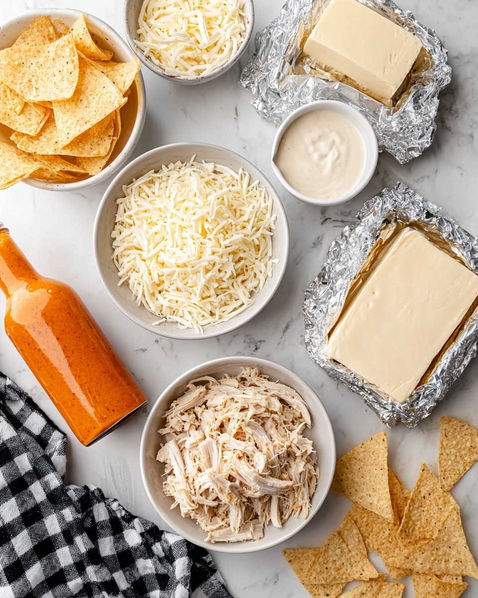 The image shows a white bowl filled with light beige shredded chicken placed next to another white bowl containing shredded white cheese. Nearby, there are two rectangular blocks of cream cheese, one placed above the other, both partially wrapped in silver foil on a white marbled surface. A small white cup filled with creamy ranch dressing sits close to the cheese, and a glass bottle of bright orange buffalo sauce lies diagonally across the surface. There are pale yellow tortilla chips in a white bowl at the top left corner and more chips scattered at the bottom right, with a black and white checkered cloth partially visible in the bottom left corner. Photo taken with an iphone --ar 4:5 --v 7