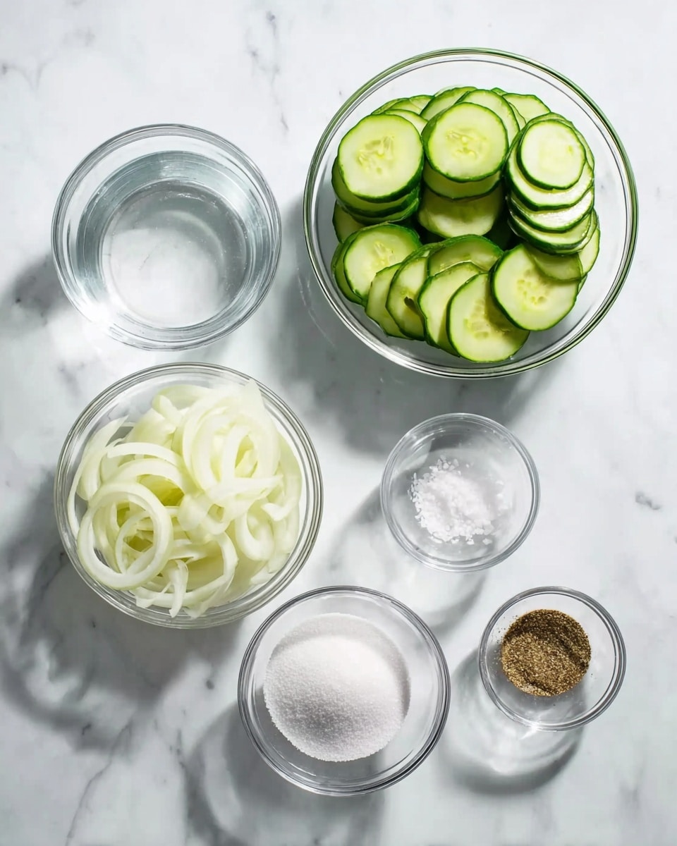 The image shows six clear glass bowls placed on a white marbled surface, each containing different ingredients. The largest bowl on the right side is filled with many thin, round green cucumber slices stacked loosely. Below it, a medium bowl holds white granulated sugar with a smooth texture. To the left, another medium bowl contains peeled and sliced onions that are thin and white with some translucency. Above the sugar, there is a smaller bowl with clear water, looking smooth and shiny. Above the water, a tiny bowl contains coarse white salt grains. To the right of the salt bowl, another tiny bowl has finely ground brown pepper with a slightly rough texture. The bowls are grouped close but separate, with clear visibility of all ingredients. The lighting is bright and clean, showing shadows that emphasize the round shapes. Photo taken with an iphone --ar 4:5 --v 7