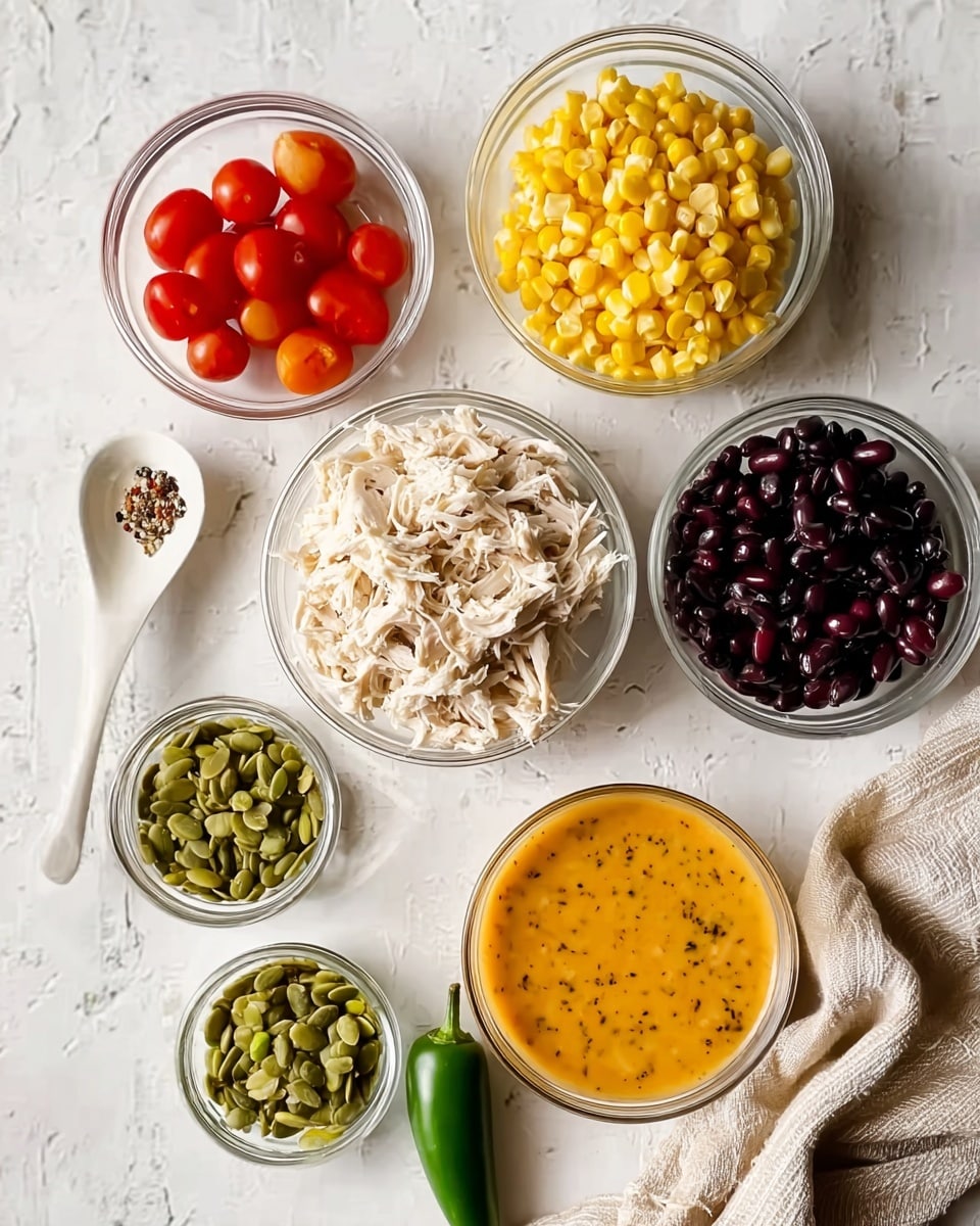 The image shows a top view of seven small clear glass bowls arranged on a white marbled surface with various colorful ingredients inside. The largest bowl in the center holds white shredded chicken. Above it to the right is a bowl filled with bright yellow corn kernels, and to its left is a bowl with vibrant red cherry tomatoes. Below the chicken are two smaller bowls with green pumpkin seeds, one slightly larger than the other. To the bottom right is a bowl filled with shiny black beans, and to the top right is a bowl of smooth orange dressing or sauce with black specks. At the bottom center near the bowls is a single fresh green jalapeño pepper, and to the left side lies a white ceramic spoon. A beige cloth is partly visible on the right side. photo taken with an iphone --ar 4:5 --v 7