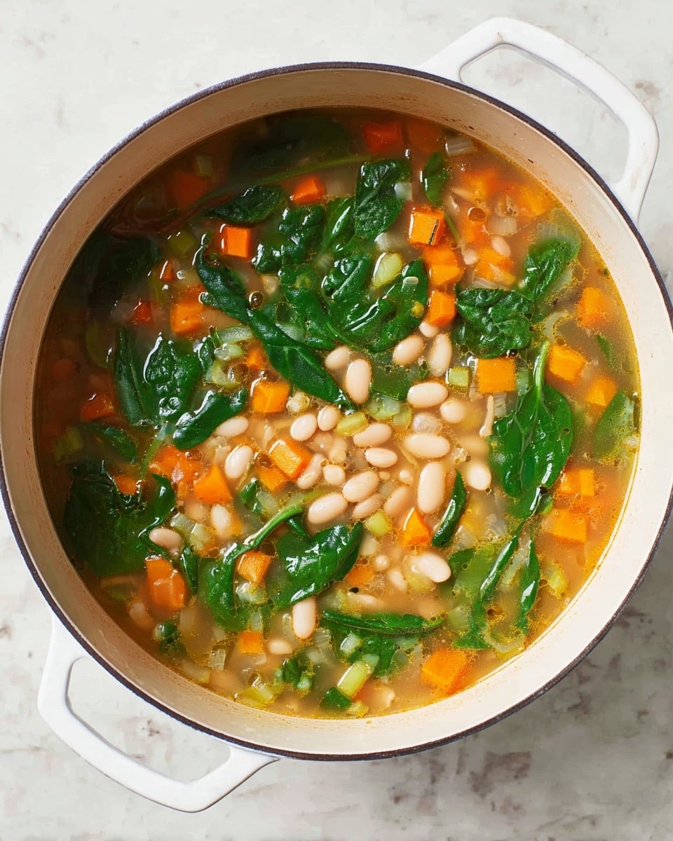 A round white pot filled with a vegetable soup showing three main layers: the bottom layer is a light brown broth, the middle layer contains small white beans and bright orange carrot cubes mixed with pale green celery pieces, and the top layer has dark green spinach leaves scattered unevenly. The pot handle and a small part of the white marbled surface underneath are visible. The photo taken with an iphone --ar 4:5 --v 7