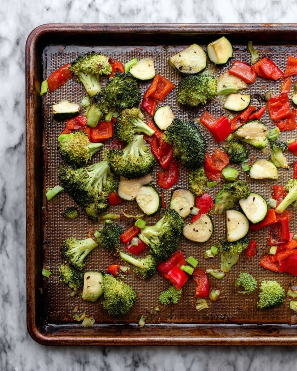 A baking tray holds scattered roasted vegetables including bright green broccoli florets, small semi-circles of light green zucchini, diced red bell peppers, and thin rounds of light green scallions. The vegetables are spread unevenly with some pieces showing light charring, and the tray has a textured, slightly darker brown surface. The background is a white marbled texture. photo taken with an iphone --ar 4:5 --v 7