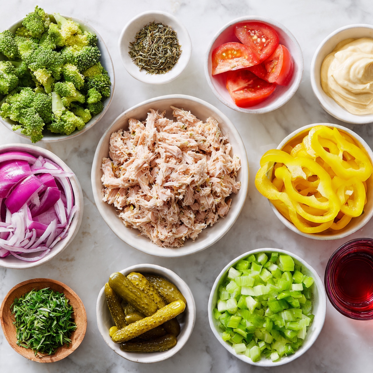 This image shows several small white bowls placed on a white marbled surface, each holding different ingredients for a meal. In the center, a bowl contains light brown shredded tuna. Around it are bowls with bright yellow banana pepper slices, green broccoli florets, chopped red onion, sliced green celery, and green lettuce leaves in a larger bowl. There are also small bowls holding pickles with a ridged texture, creamy pale yellow mayonnaise, a small red tomato with a green stem, a bowl of finely chopped purple onion, some dried green herbs, and a small glass of red liquid. The colors are fresh and vibrant, giving a clean and healthy feel. photo taken with an iphone --ar 4:5 --v 7