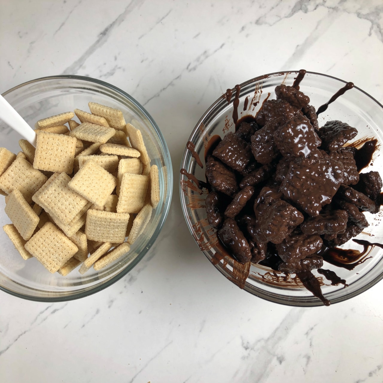 The image shows two clear glass bowls on a white marbled surface, side by side. The left bowl is filled with square, light beige cereal pieces, dry and with a toasted texture, while a white spoon is partially visible mixing the cereal. The right bowl contains the same cereal pieces now fully coated in a thick, dark chocolate sauce, making them look shiny and sticky with uneven clumps. Some chocolate drips and smudges are seen on the bowl sides. photo taken with an iphone --ar 4:5 --v 7